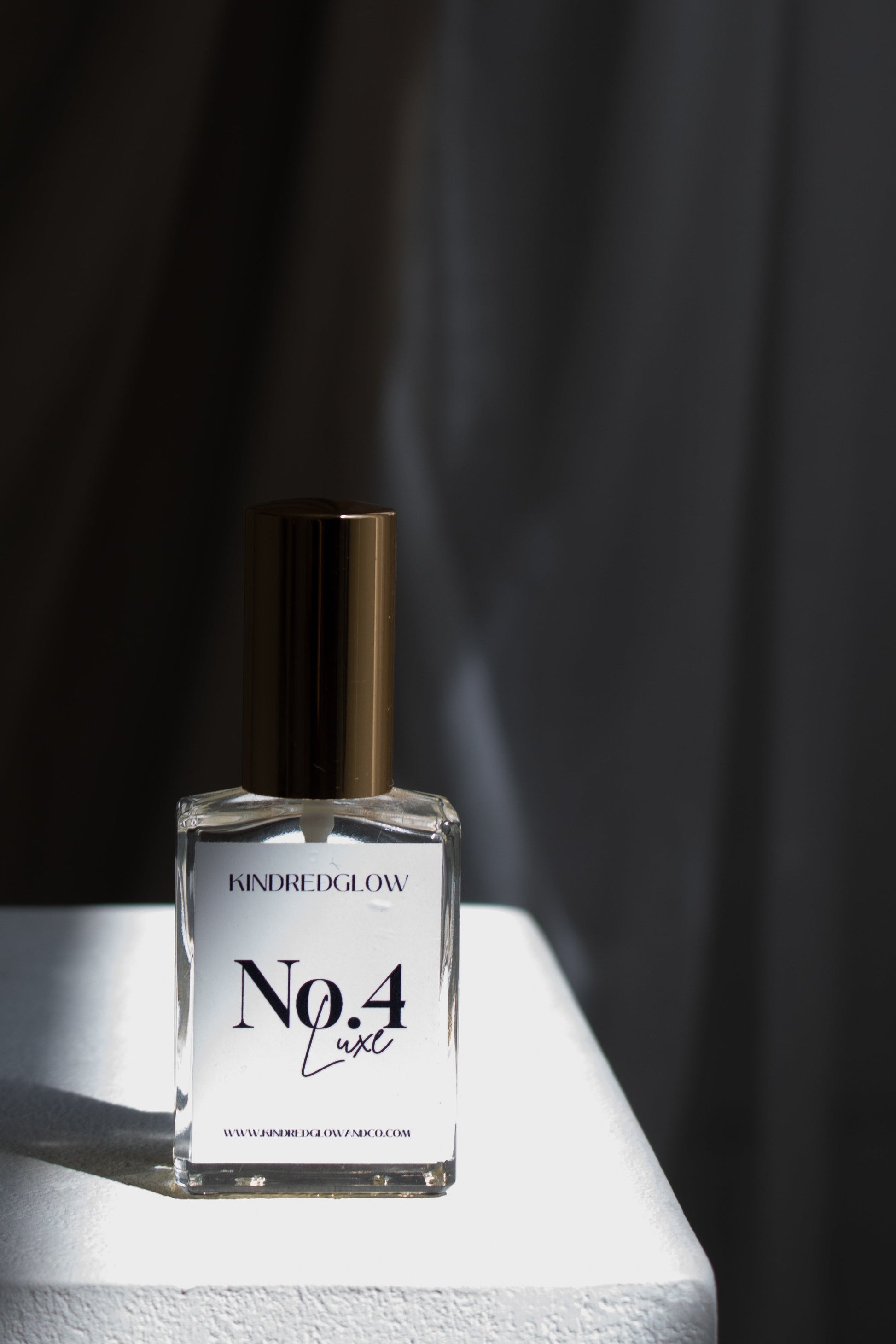 Clear glass bottle with label on a white surface against a black curtain