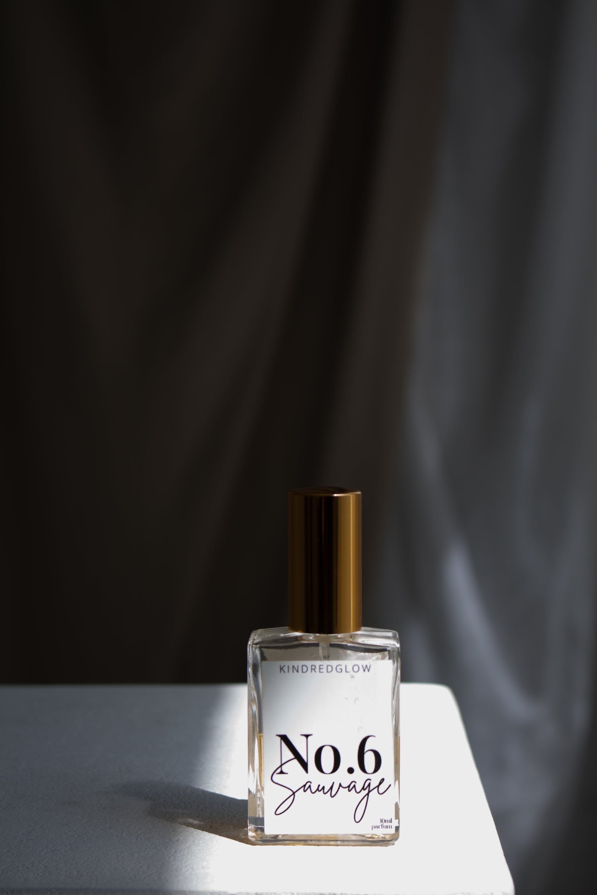 Perfume bottle labeled 'No. 6 Savage' on a reflective surface with a dark background
